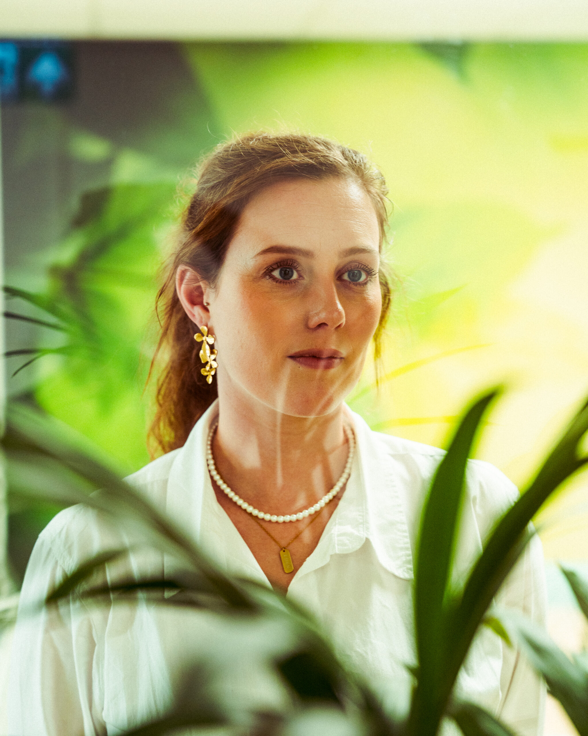 Woman with green surroundings looking through window